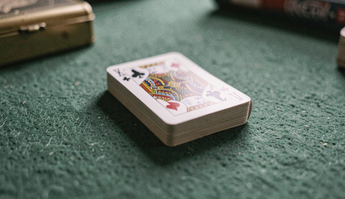 Closed playing card deck face down on a felt table with a small lock of the brass case visible at the corner
